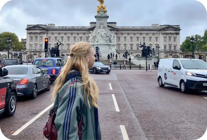 Chica de espaldas ante el palacio de Buckingham y el monumento a la reina Victoria en Londres