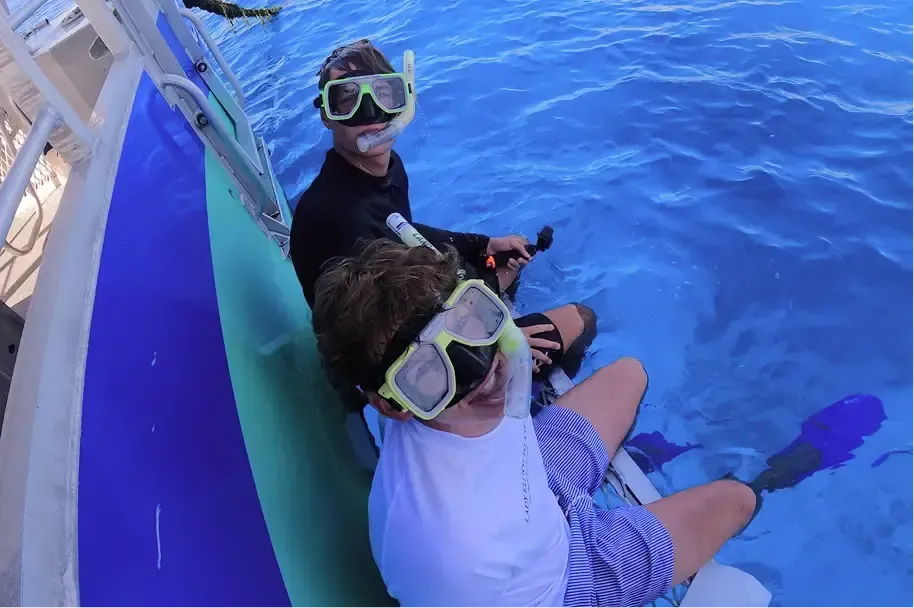 Due ragazzi con maschere da snorkeling seduti sul bordo di una barca