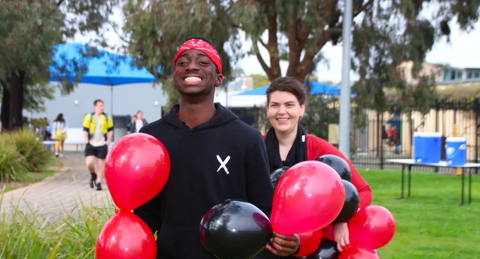 Due persone si trovano nel parco con palloncini rossi e neri nel campus dell'Avenues College.
