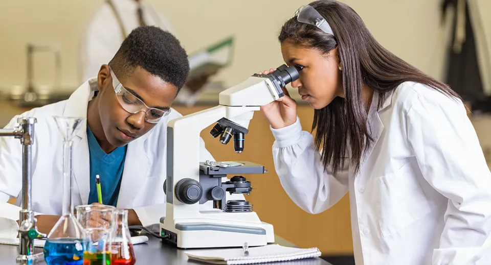 Due studenti del Worksop College esaminano qualcosa in laboratorio con un microscopio.