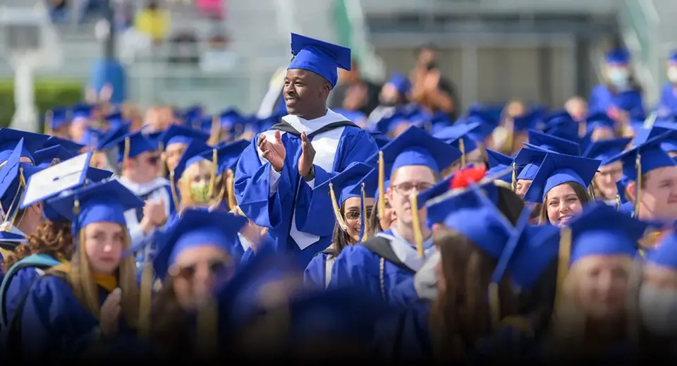 Un grande gruppo di diplomati in toga blu si trova insieme davanti alla Erin District High School.
