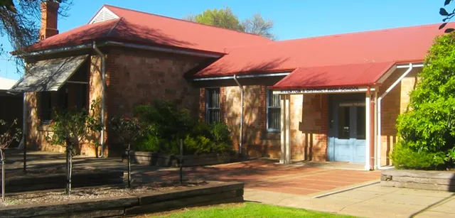 L'edificio in stile adobe con tetto in tegole rosse si trova nel campus della Riverton and District High School, circondato dal verde.