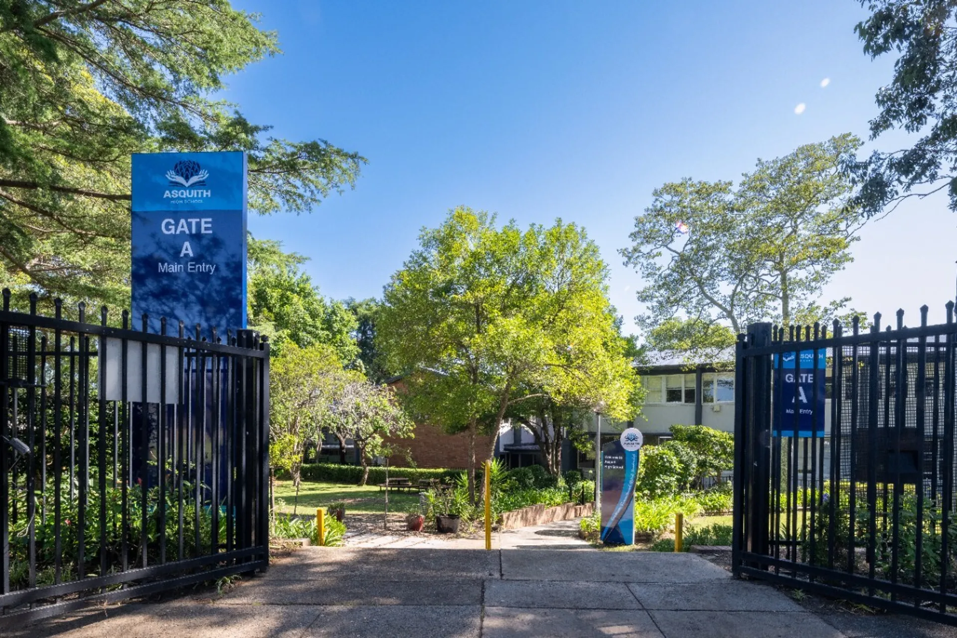 L'ingresso principale aperto della Asquith High School con un cartello blu e alberi sullo sfondo.