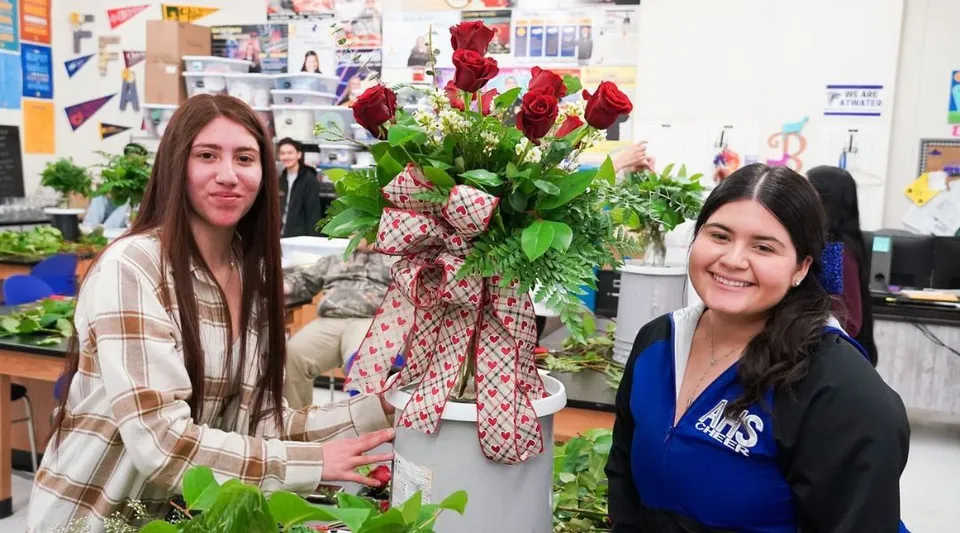 Due studentesse del Merced Union High School District si trovano in un negozio di fiori tra mazzi di fiori colorati e piante verdi.