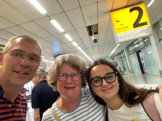 Selfie di famiglia all'arrivo in aeroporto sotto il cartello degli arrivi