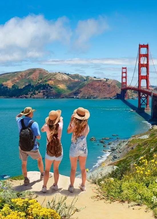 Tres jóvenes con sombrero de paja contemplan de espaldas el puente Golden Gate