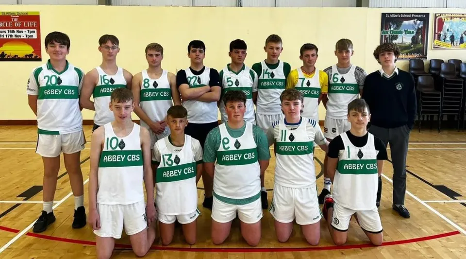Un gruppo di studenti della The Abbey School posa insieme nella palestra come squadra di basket.