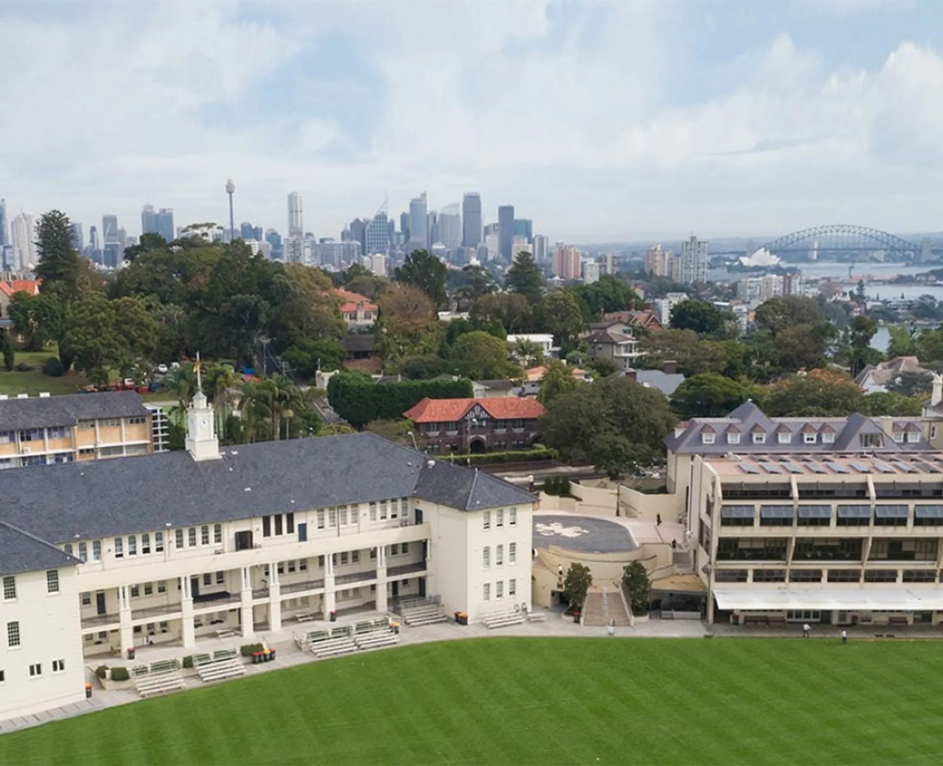 Il campus del The Scots College con un campo sportivo verde e lo skyline di Sydney sullo sfondo.