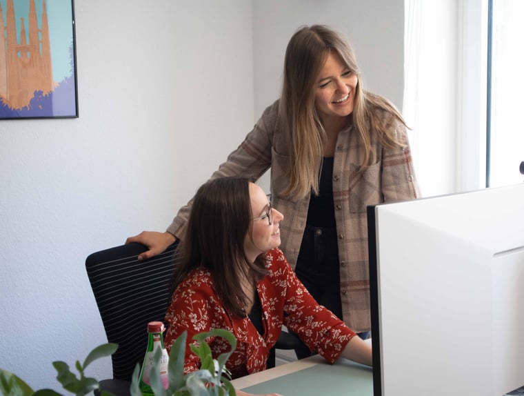 Zwei Kolleginnen besprechen sich gemeinsam vor einem Bildschirm im Büro