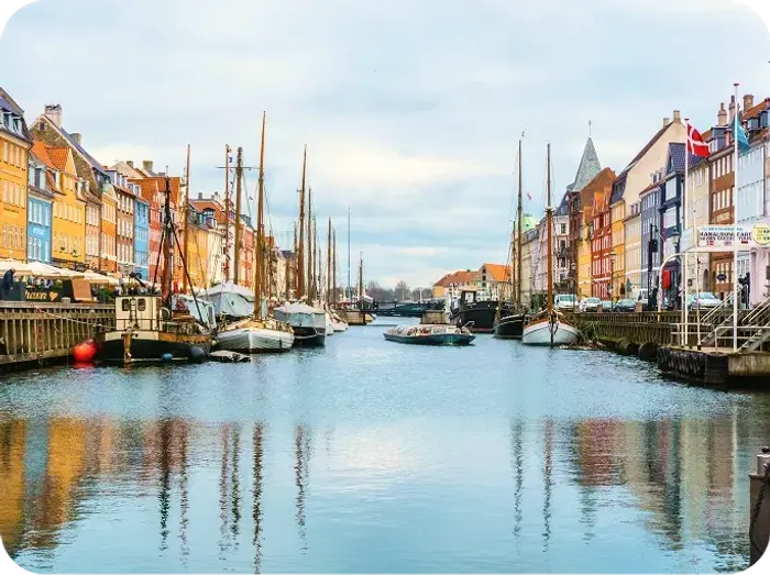 Barche a vela ormeggiate lungo il canale di Nyhavn tra le case colorate di Copenaghen