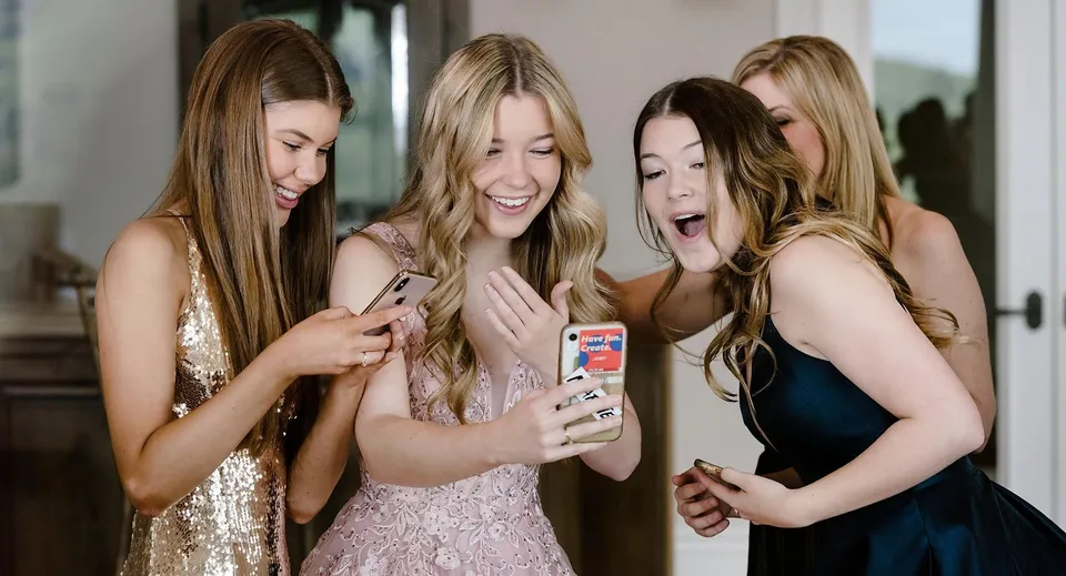 Quattro studentesse del Dominican College Sion Hill guardano insieme sorridenti uno smartphone in un ambiente interno.