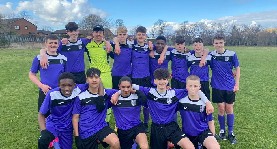 Studenti della Holy Rood High School sul campo da calcio con le loro maglie viola e gialle.