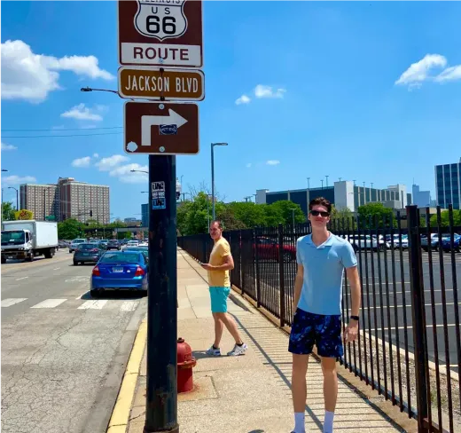 Due ragazzi sotto un cartello della Route 66 e Jackson Blvd in una strada di città negli Stati Uniti.