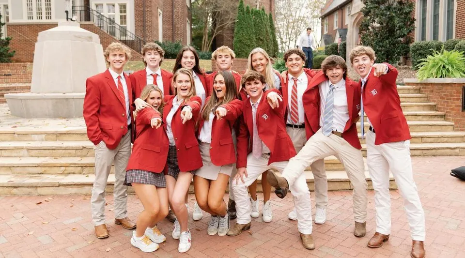 Un gruppo di studenti della Baylor School è insieme sulle scalinate del campus con edifici in mattoni sullo sfondo.