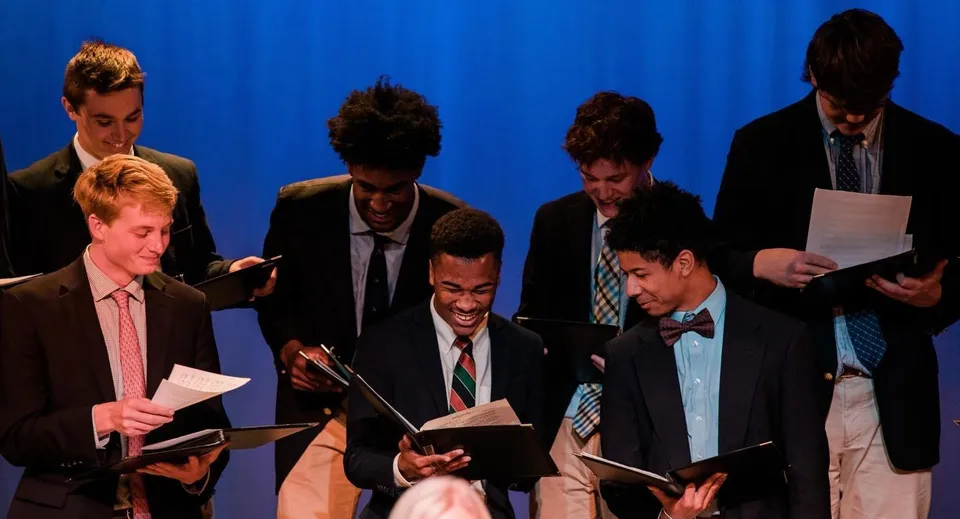 Un gruppo di uomini in abito formale sta davanti a uno sfondo blu presso la Virginia Episcopal School.