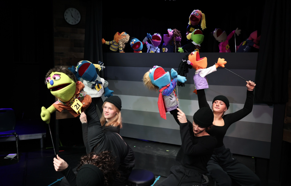 Schülerinnen sind auf der Bühne und führen ein Theaterstück mit Puppen auf