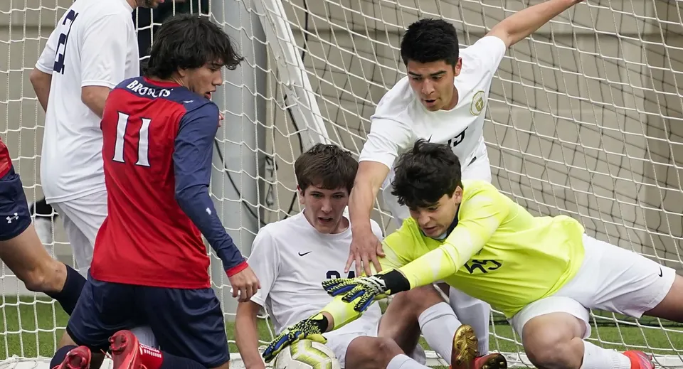 Studenti della St. Brendan’s Community School ricevono istruzioni insieme sul campo da calcio durante l'allenamento.