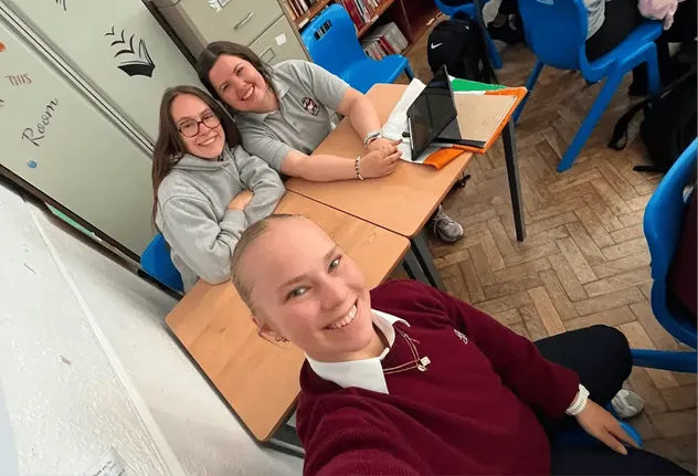 Drei Schülerinnen machen ein Selfie im Klassenzimmer in Irland