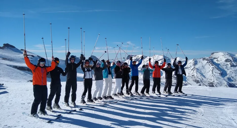 Un gruppo di studentesse e studenti della Presentation Secondary School (Thurles) si trova su un pendio montano innevato sotto un cielo limpido.
