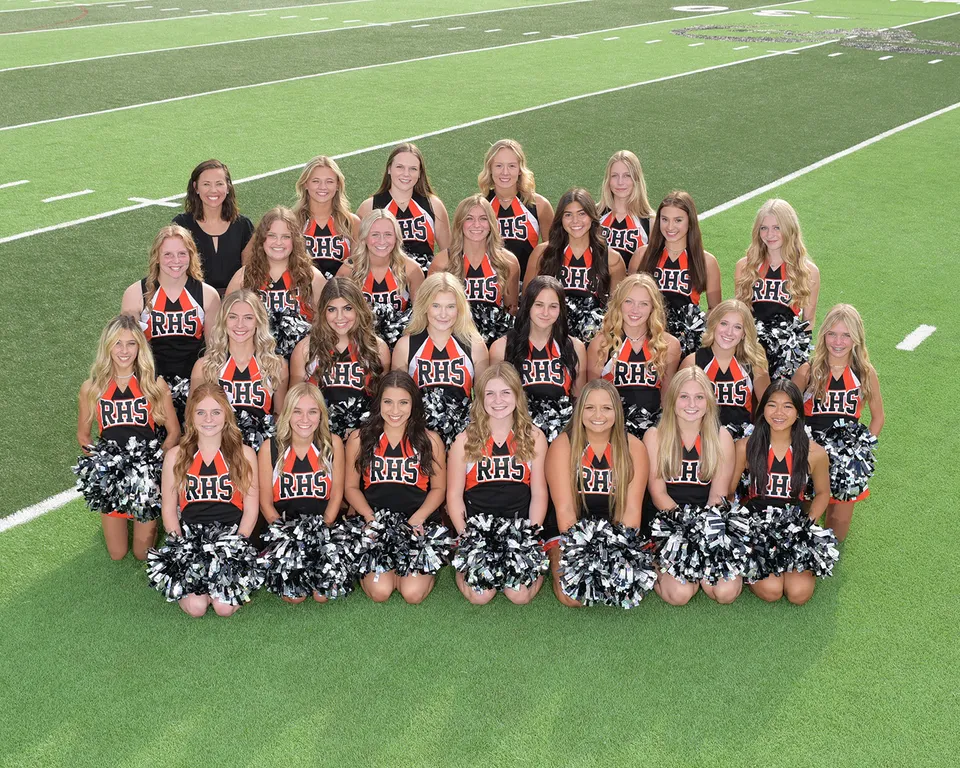 Le cheerleader della Rockford High School mettono in posa in divise abbinate su un campo sportivo verde.