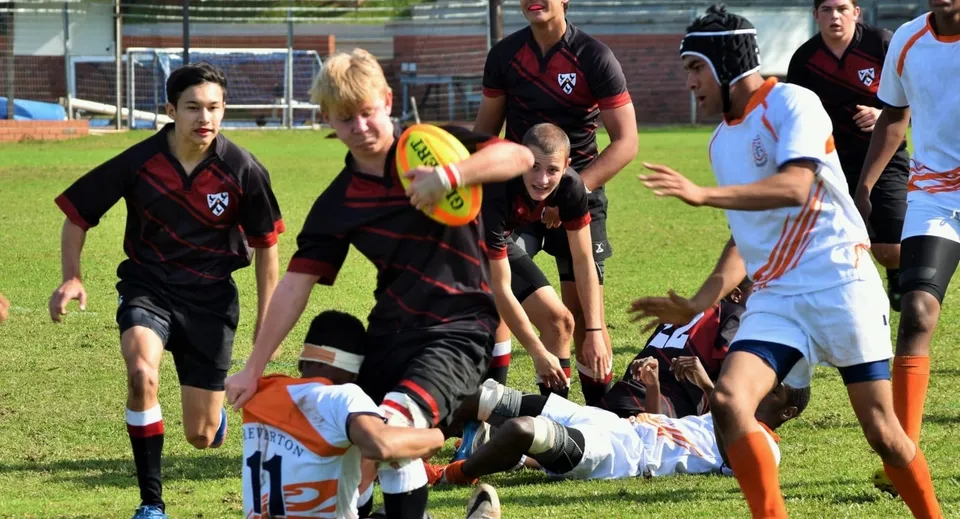 Studenti del Slindon College partecipano a un'attività sportiva su un campo erboso.