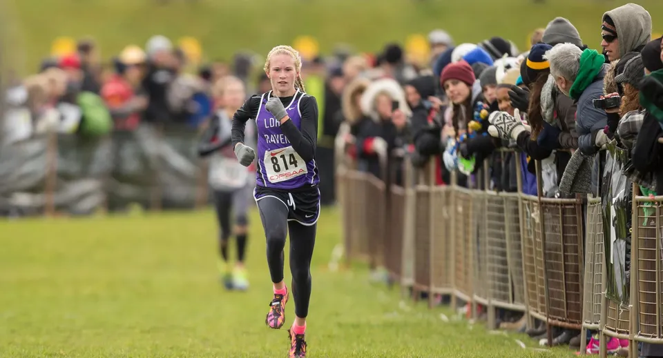 Una runner corre su un prato davanti al pubblico nel campus della Longfields-Davidson Heights Secondary School.