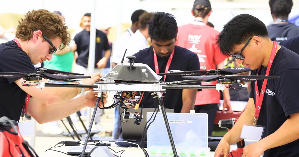 Tre studenti della Senator Gershaw School assemblano un grande drone su un tavolo all'aperto.