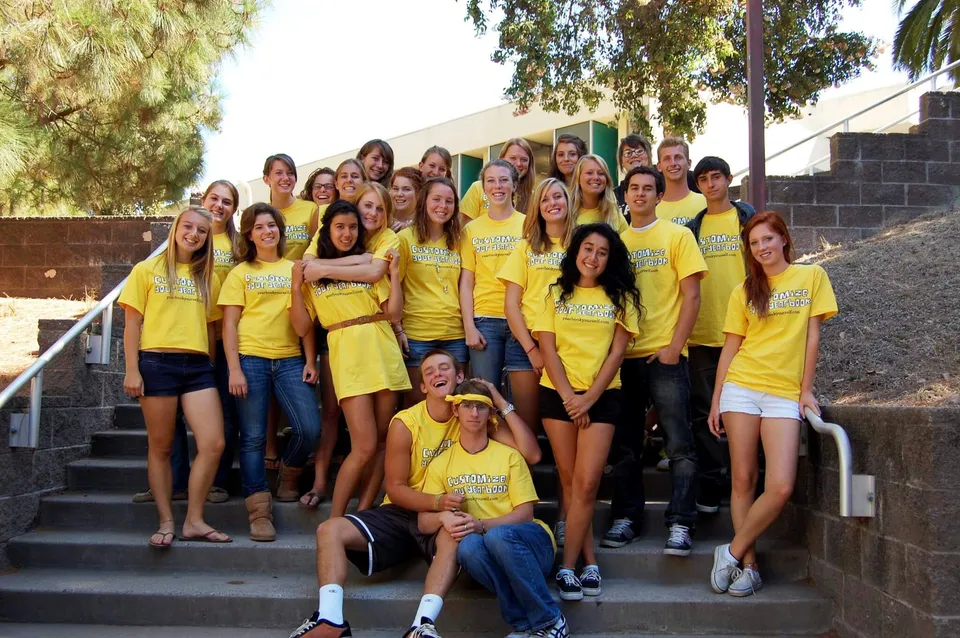 Un gruppo di studentesse della San Luis Obispo High School è seduto su gradini esterni davanti a un edificio e ad alcuni alberi.