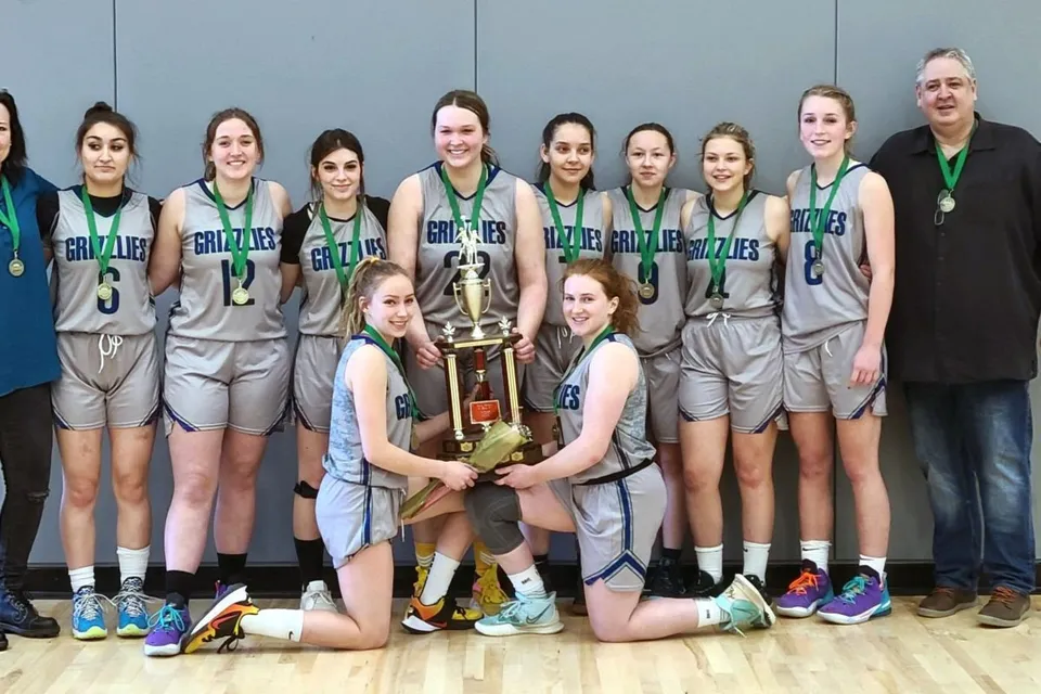 Studentesse della Shas Ti Kelly Road Secondary School posano con un trofeo nella palestra.