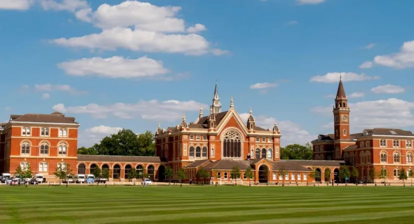 Il maestoso edificio principale in stile gotico del Dulwich College è circondato da un prato ben curato e da un cielo azzurro.