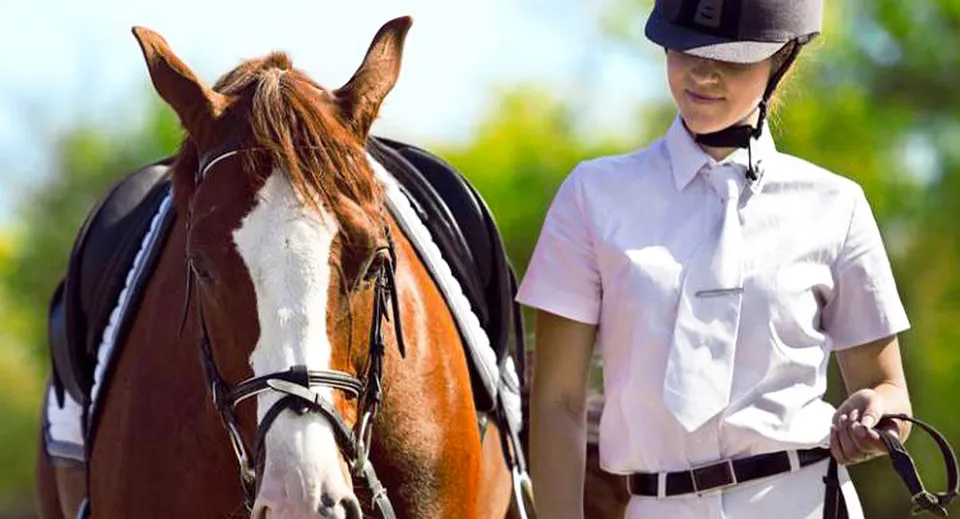 Una persona accanto a un cavallo bianco e marrone su un prato nel campus della Brookswood Secondary School.