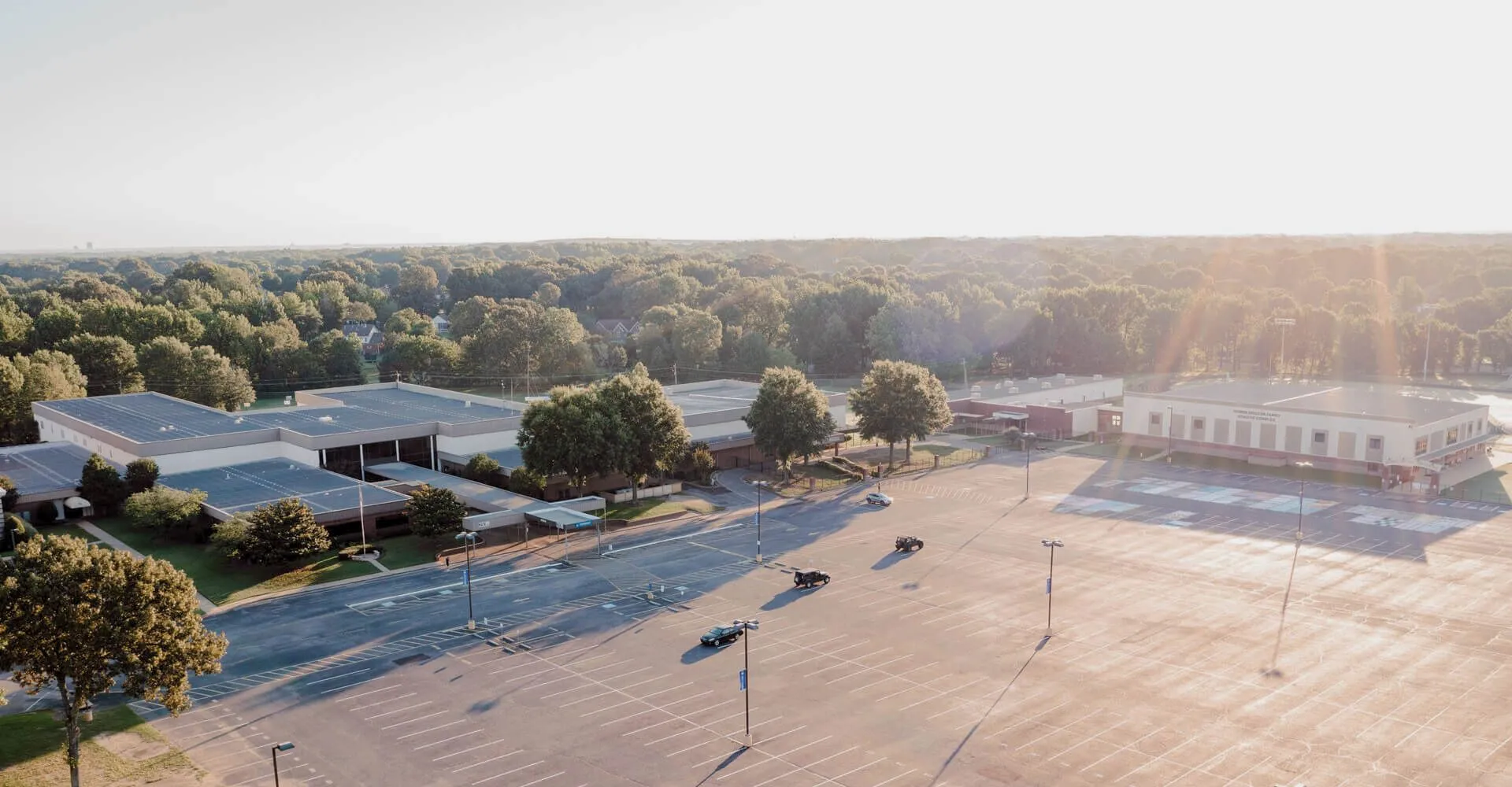 Un grande parcheggio all'aperto con alberi e edifici scolastici sullo sfondo nel campus della Northpoint Christian School.