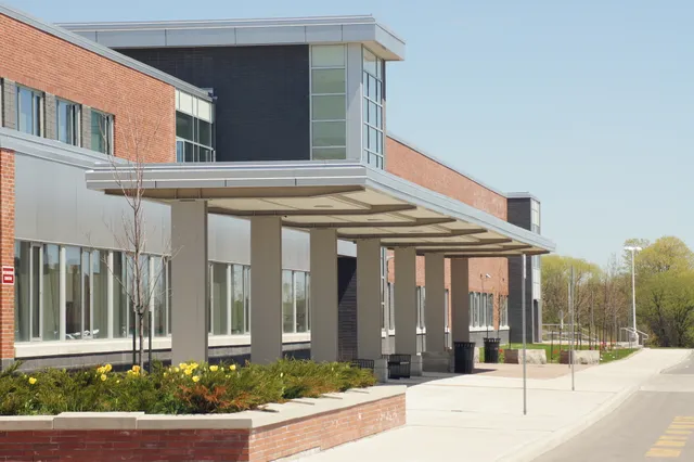 Das moderne mehrstöckige Gebäude der Maxwell Heights Secondary School mit Glas- und Backsteinfassade unter klarem blauem Himmel.