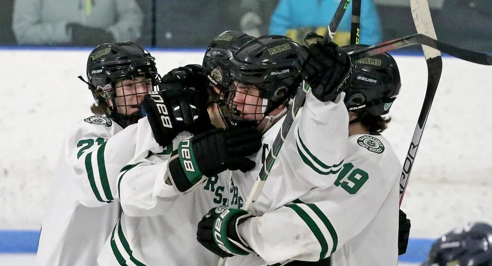 Un gruppo di studenti con maglie bianche e verdi gioca a hockey sulla pista di ghiaccio della Pender Harbour Secondary.