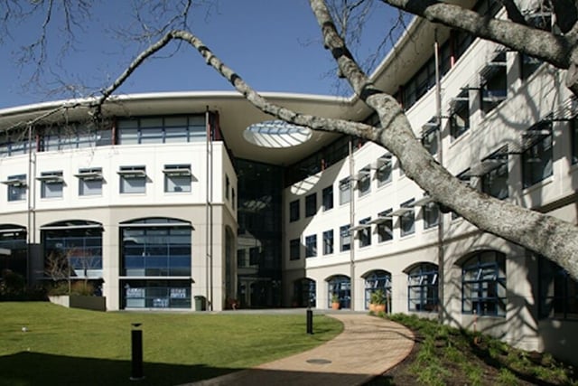 Das moderne, geschwungene Gebäude der Diocesan School For Girls mit großen Fenstern steht vor einer grünen Wiese und einem kahlen Baum.