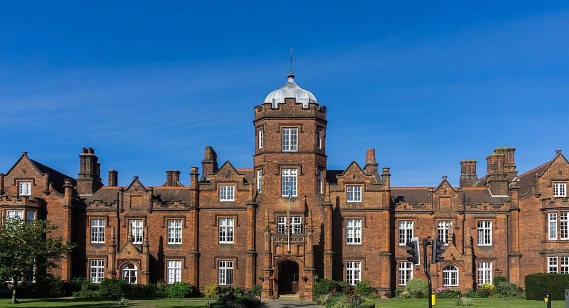 L'edificio storico in mattoni rossi con torre nel campus della Ipswich School si staglia contro un cielo blu limpido.