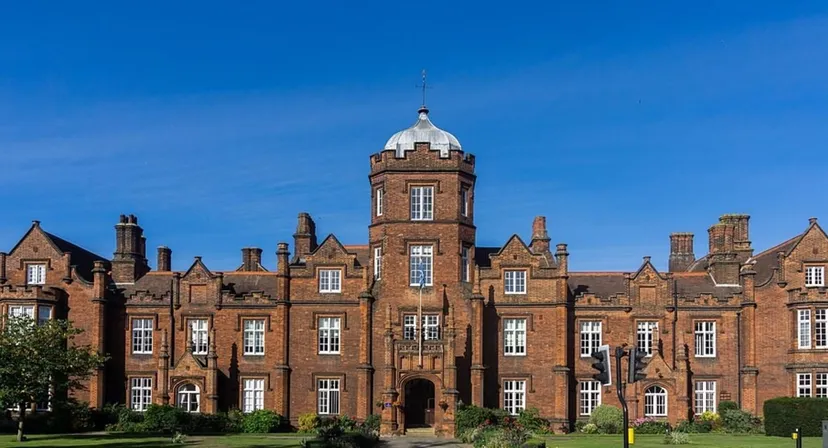 L'edificio storico in mattoni rossi con torre nel campus della Ipswich School si staglia contro un cielo blu limpido.