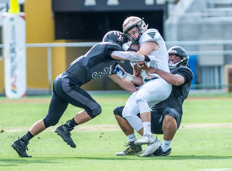 Due giocatori di football della Green Fields High School eseguono una scena di placcaggio sul campo da gioco.