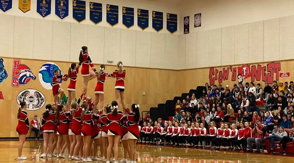 Un gruppo di cheerleader si esibisce in uno spettacolo di danza sul palco della Alberni District Secondary School davanti al pubblico.