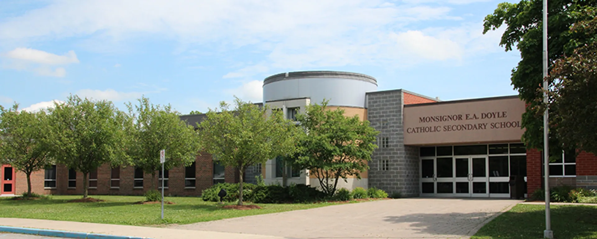 Il moderno edificio scolastico della Monsignor Doyle Catholic Secondary School con struttura circolare si trova circondato da un prato ben curato e da un verde paesaggio.