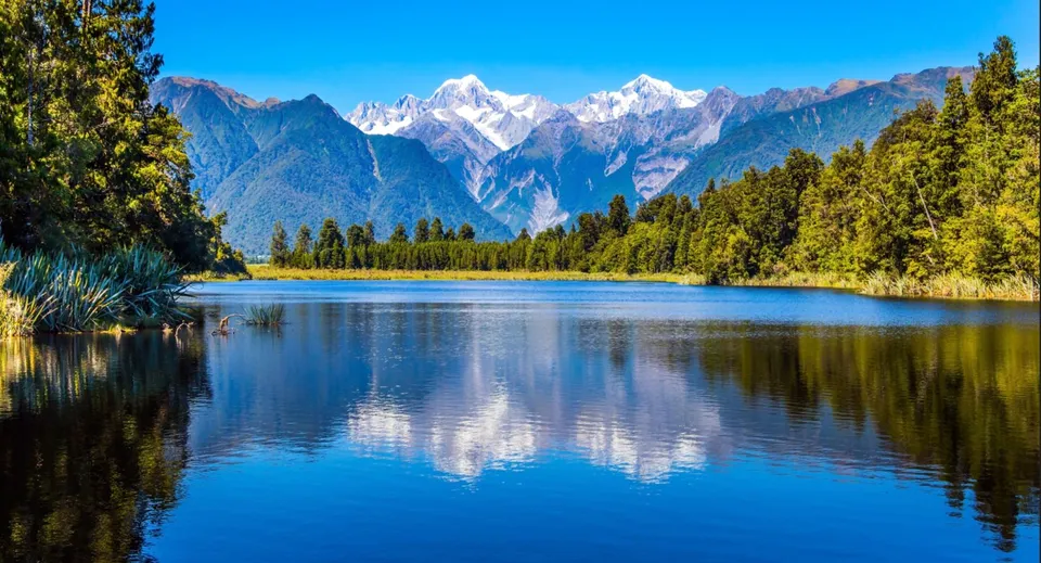 Un lago tranquillo con il riflesso delle montagne innevate e delle fitte foreste vicino al Marist College.