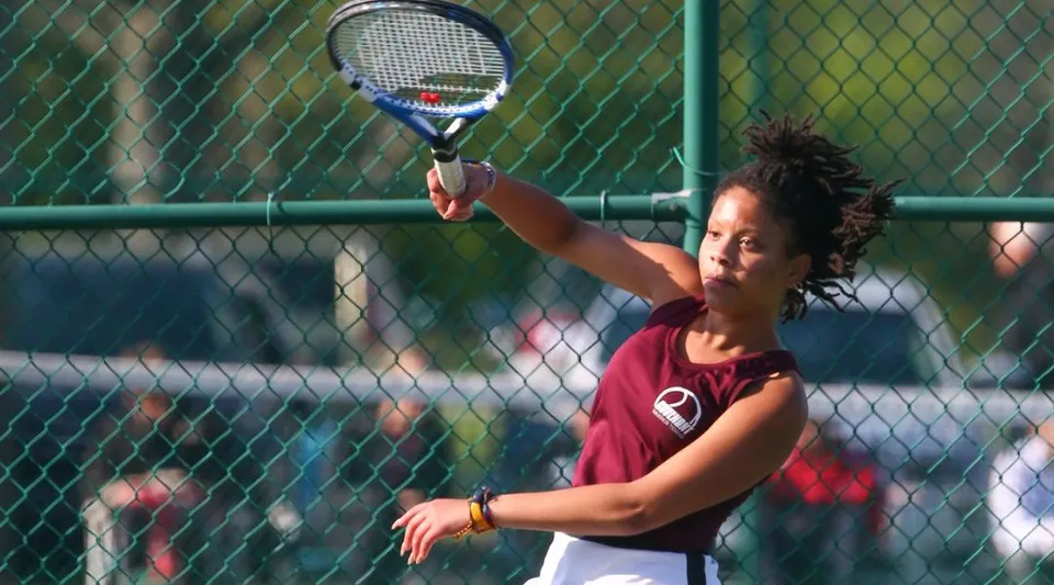 Una studentessa della Covenant Christian High School sta sul campo da tennis con una racchetta.