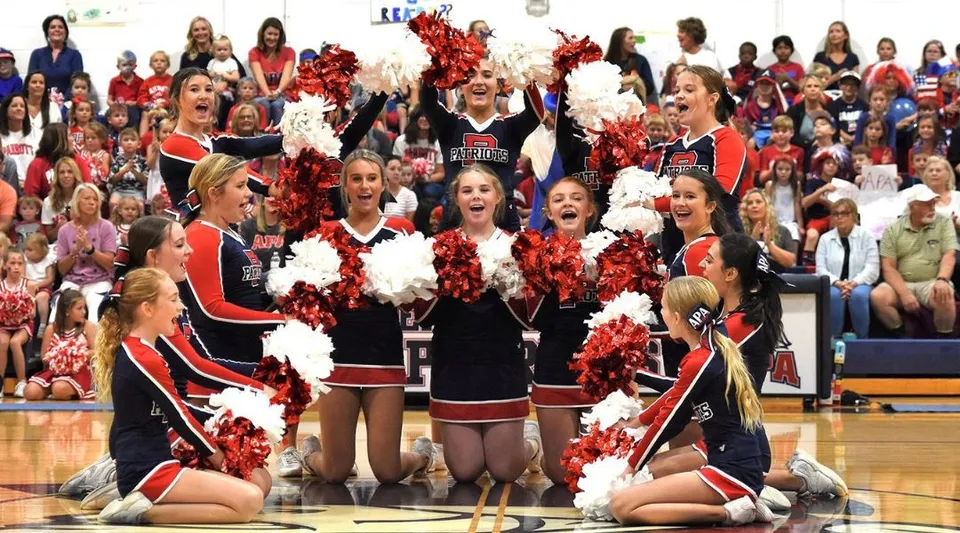 Un gruppo di cheerleader della Arendell Parrott Academy si esibisce sul campo da basket davanti a un folto pubblico.