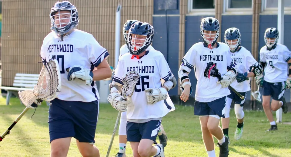 Un gruppo di giovani atleti in divisa da lacrosse si trova sugli impianti sportivi della Heathwood Hall Episcopal School.
