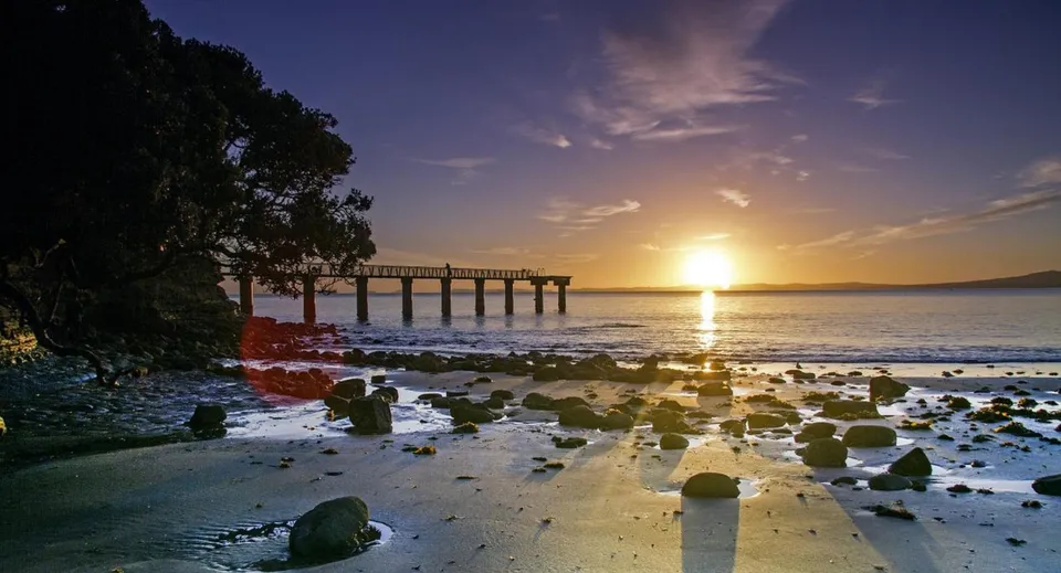 Un pontile di legno si estende al tramonto in acque calme nei pressi della Auckland Grammar School.