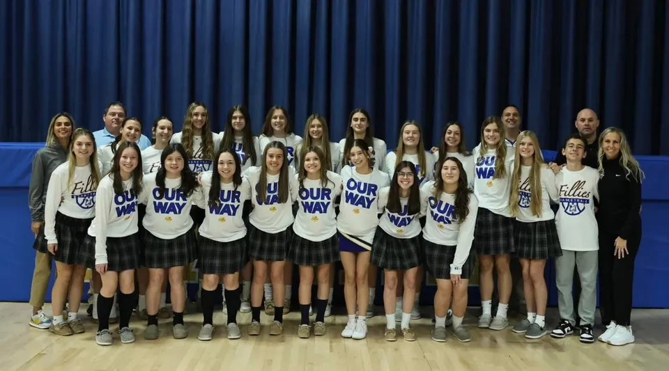 Un gruppo di studentesse in divisa davanti a una tenda blu nel campus della Marian Catholic High School.