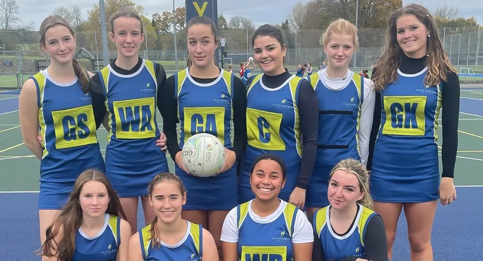 Un gruppo di giovani studentesse che giocano a netball posa insieme sul campo da gioco della Clayesmore School.