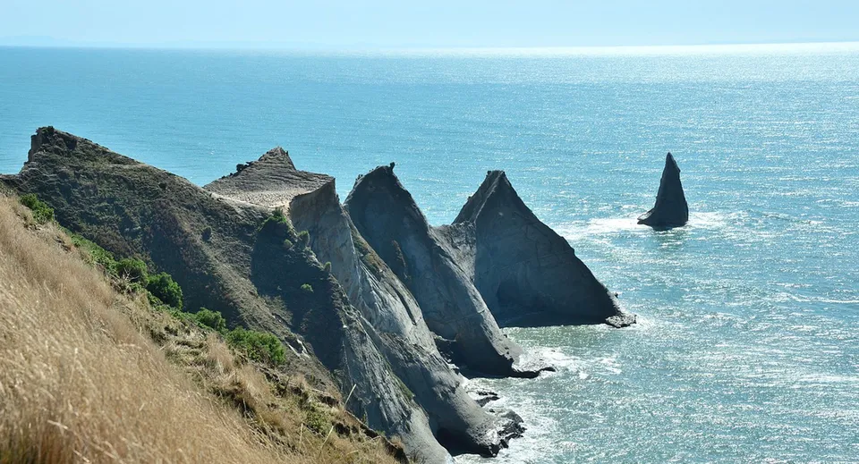 Spettacolari formazioni rocciose sulla costa con un mare calmo davanti al Sacred Heart College Napier.