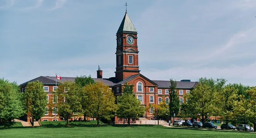 L'Upper Canada College mostra un edificio in mattoni vincolato come monumento storico con un'alta torre dell'orologio immerso in un contesto simile a un parco.