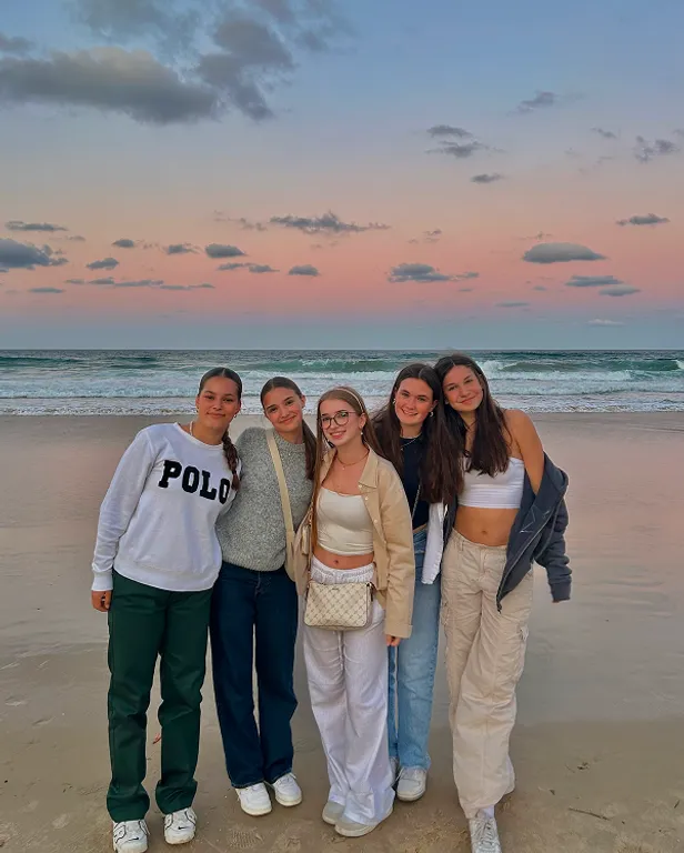 Cinque studentesse su una spiaggia al tramonto in Australia
